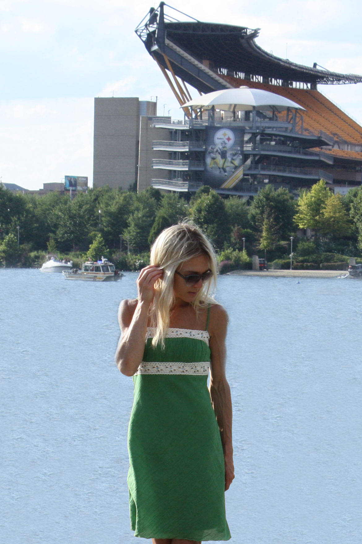 girl standing on the shore at the Three Rivers Regatta with riverboats and Heinz Stadium in the background