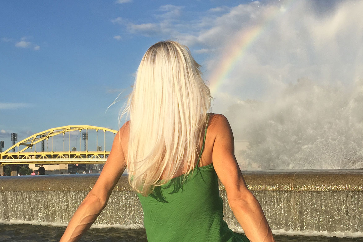 girl looking at a rainbow at the fountain of Point State Park in Pittsburgh